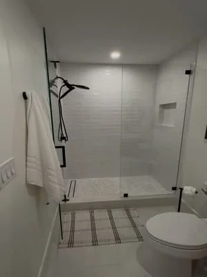 Modern bathroom with frameless glass shower, subway tile walls, and striped floor tile