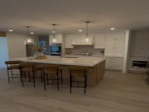 Modern kitchen with white cabinetry, wood island, bar seating, and recessed lighting