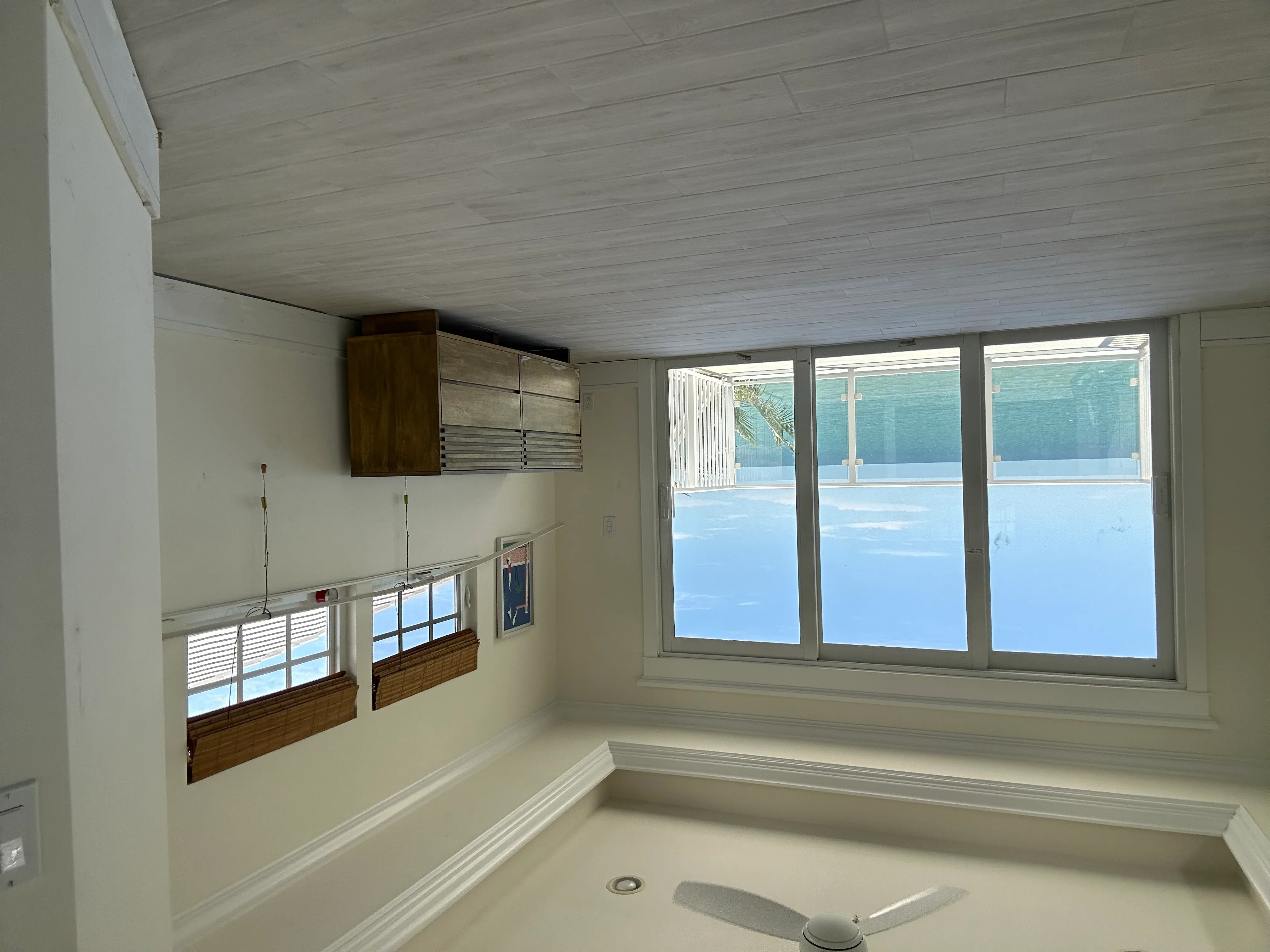 Kitchen with wood cabinetry, white shiplap ceiling, and large sliding glass doors overlooking pool area