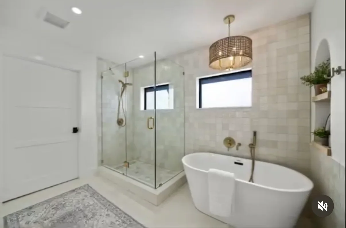 Modern bathroom with glass shower, freestanding tub, marble tile, and brass fixtures