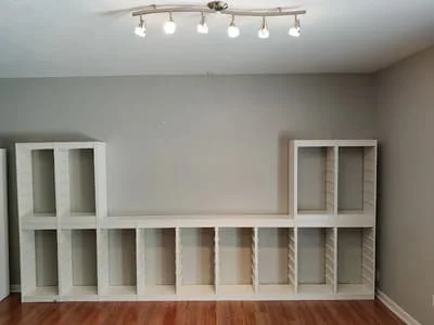 White built-in shelving units with open compartments and track lighting on wall