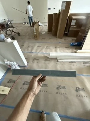 Subfloor underlayment installation with measurement tape and protective coverings on kitchen floor