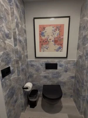 Marble-look tile powder room with black toilet, sink, and recessed lighting