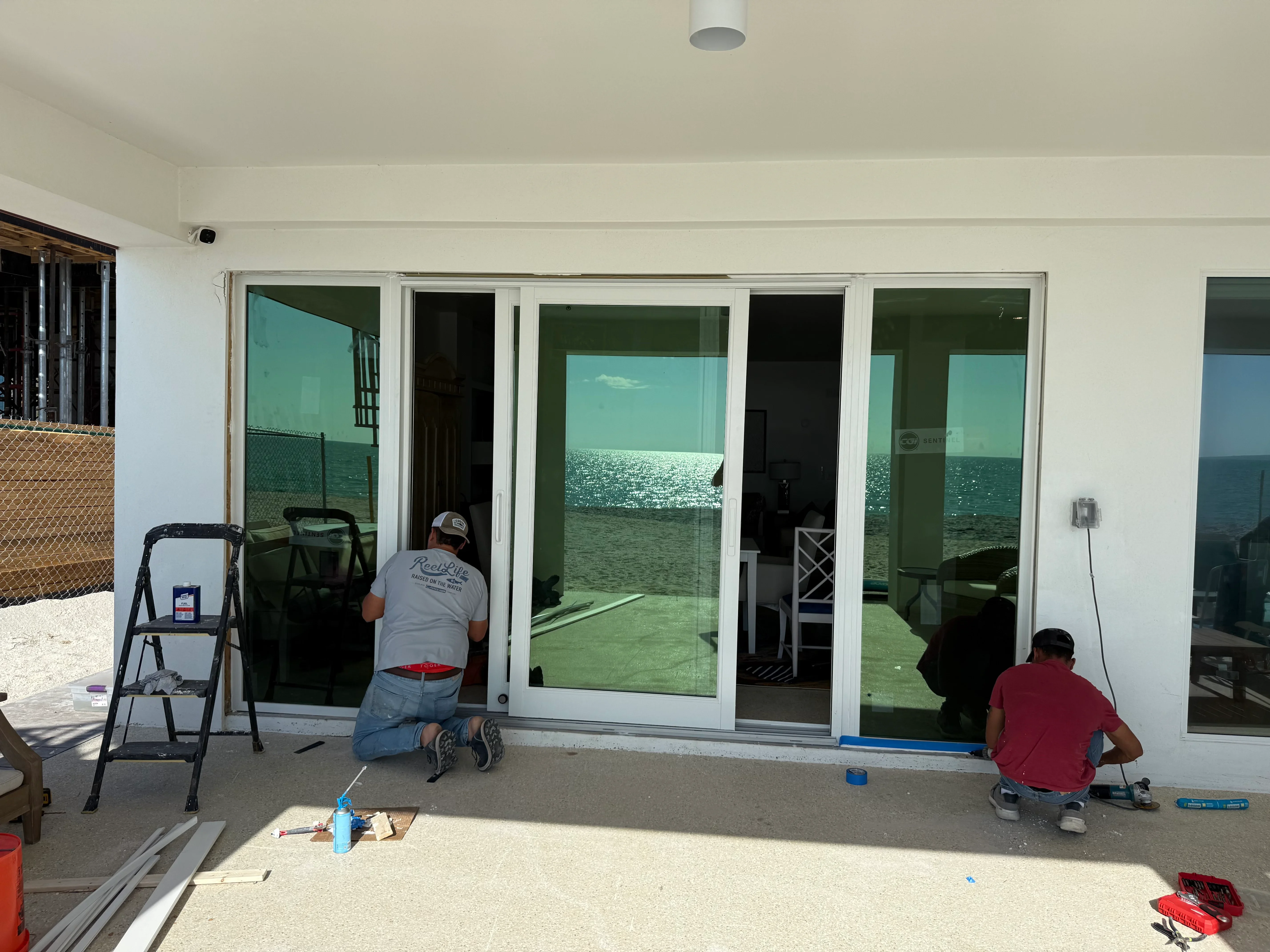 Multi-panel sliding glass doors with white frames being installed during construction